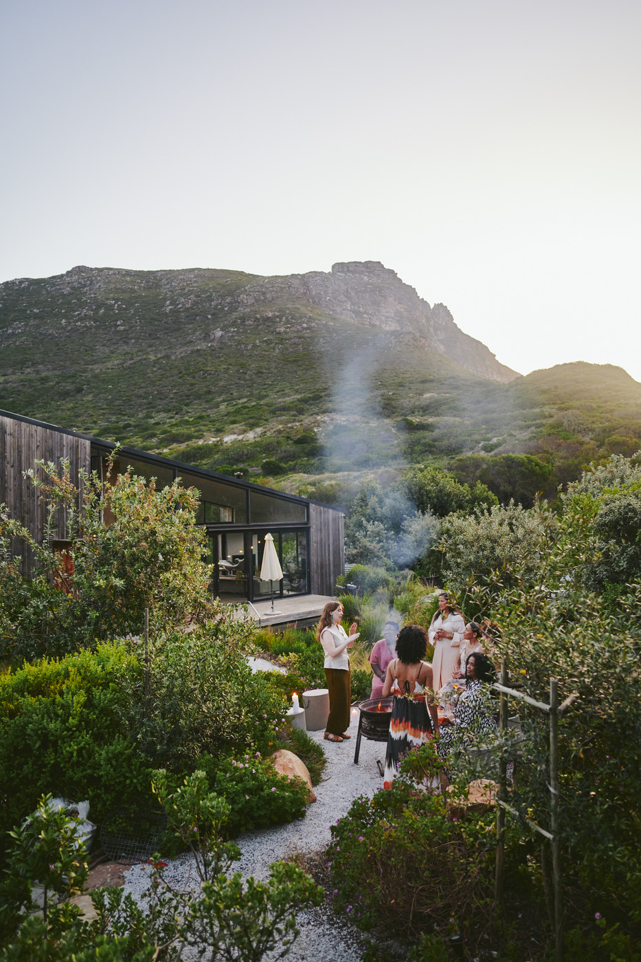 A group of people enjoying an outdoor retreat with a firepit in an arid highland environment.